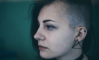Woman with an edgy shaved haircut looks sad and defeated