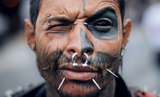 a man with black face paint and piercings on his nose
