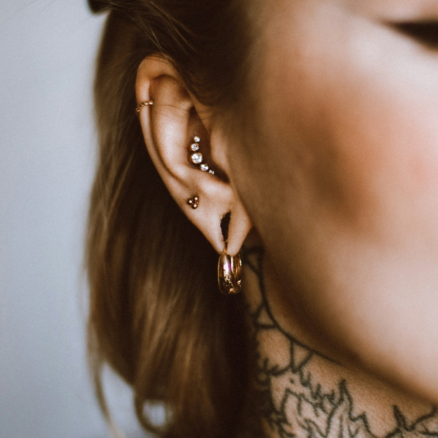 a woman with a tattoo on her neck and behind her ear