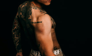 Tattooed man looking over his shoulder against black background