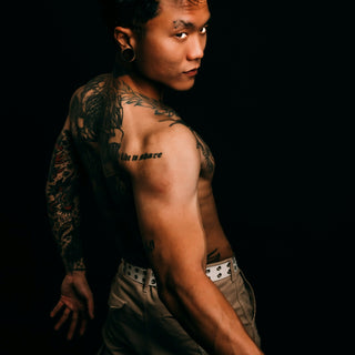 Tattooed man looking over his shoulder against black background