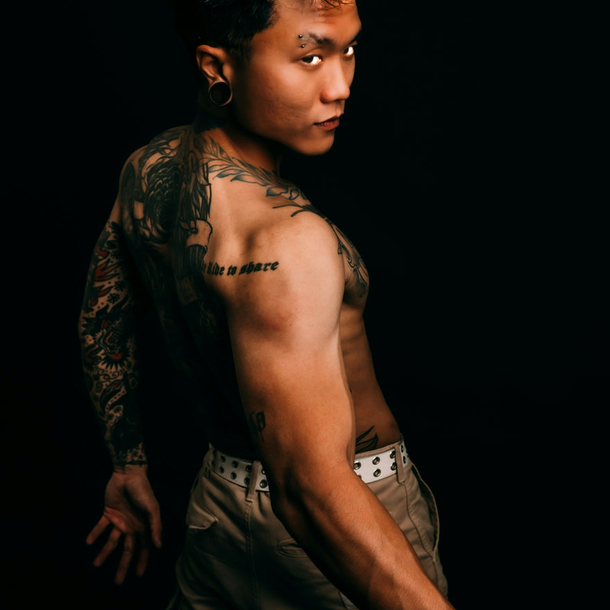 Tattooed man looking over his shoulder against black background