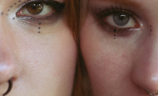 Two women with elaborate makeup and piercings close-up facial features