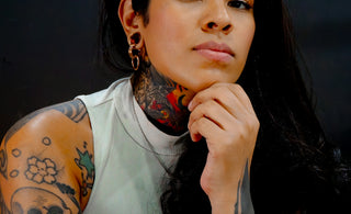 Young woman with extensive tattoos and dark hair.