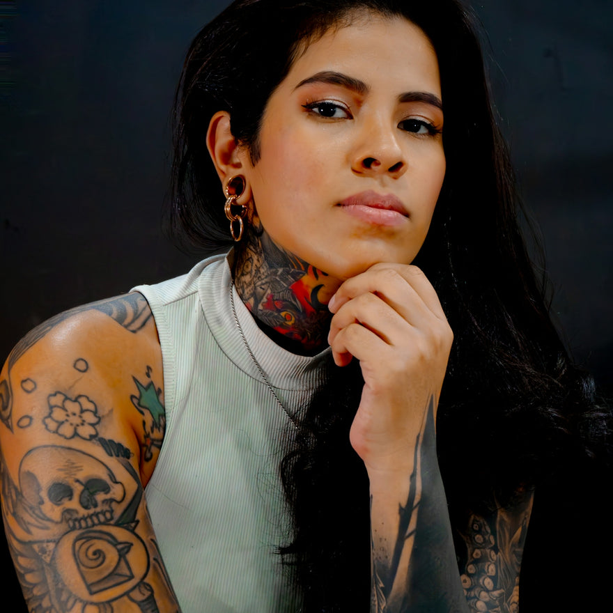 Young woman with extensive tattoos and dark hair.