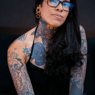 Woman with extensive tattoos and glasses