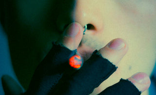 Man with nose ring smoking with black fingerless gloves