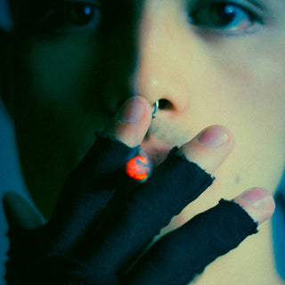 Man with nose ring smoking with black fingerless gloves