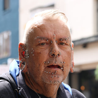 Elderly man with numerous facial piercings and jewelry