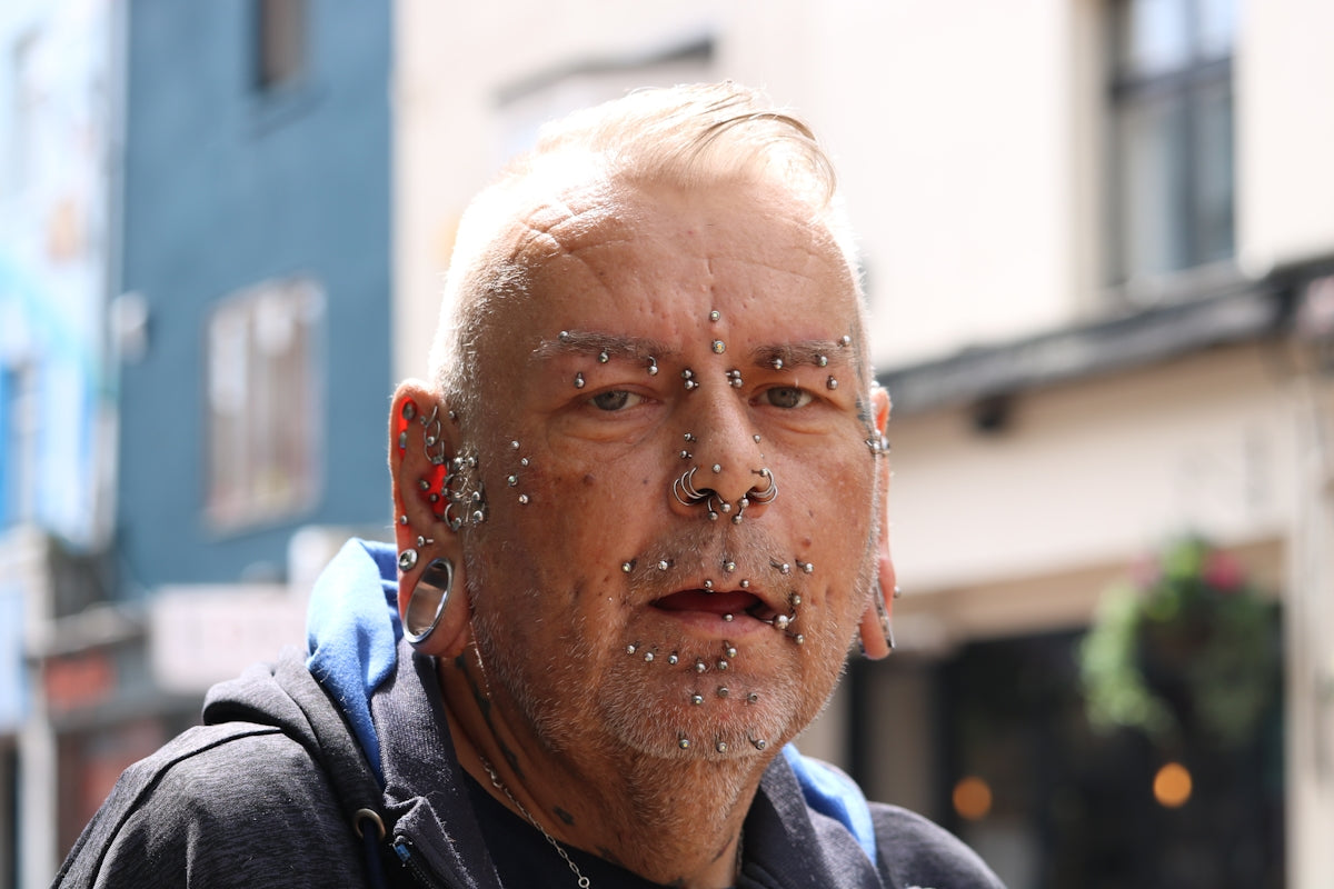 Elderly man with numerous facial piercings and jewelry