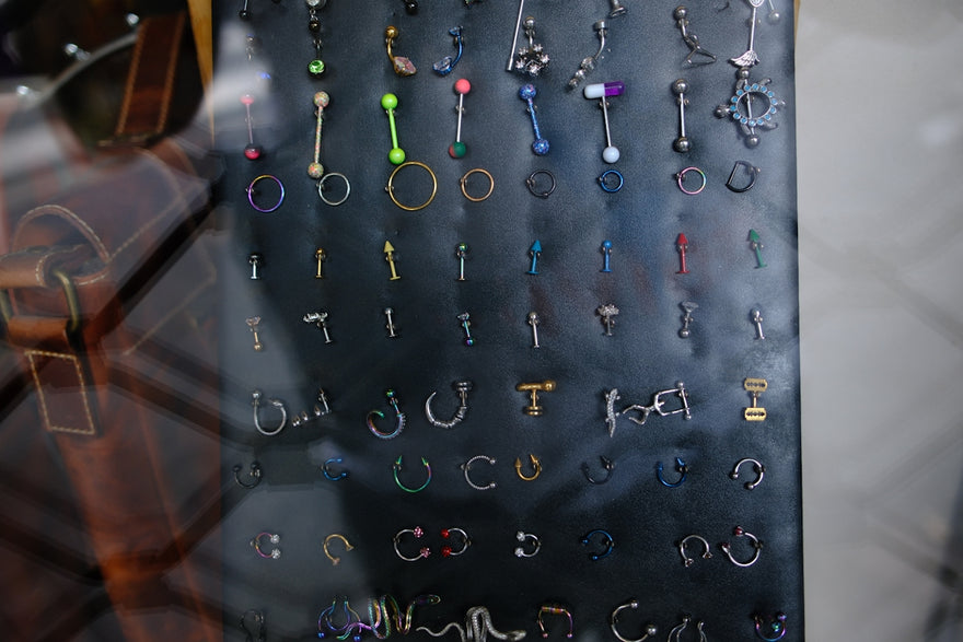 Many colorful body piercings and earrings on a dark display.