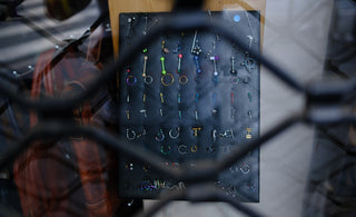 A display of body piercings seen through a metal grate.