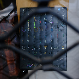 A display of body piercings seen through a metal grate.