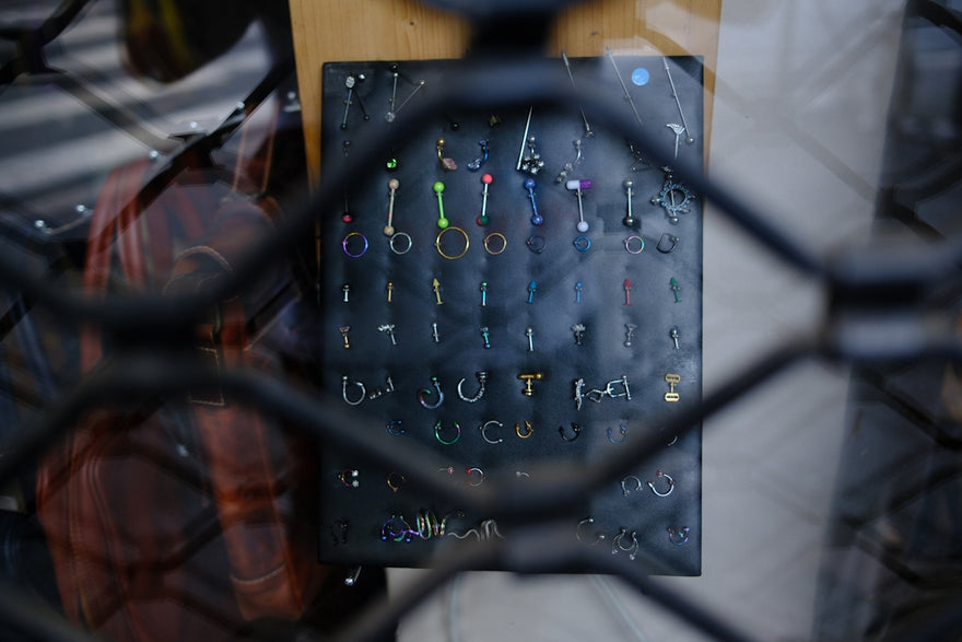 A display of body piercings seen through a metal grate.