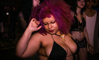 Woman with vibrant pink hair dancing in a dark club
