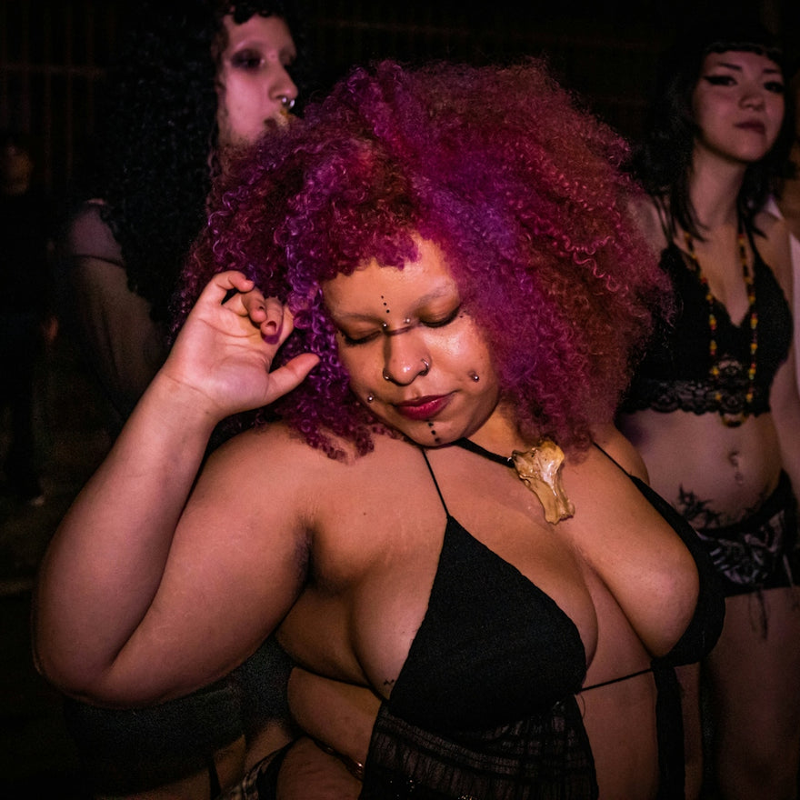 Woman with vibrant pink hair dancing in a dark club