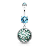 A silver-toned belly button ring with a dangling charm. The top barbell features a round light blue gemstone, and the dangling element has a large circular silver filigree frame with a green and blue patterned center and a smaller light blue gemstone at the top.