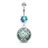 A silver-toned belly button ring with a dangling charm. The top barbell features a round light blue gemstone, and the dangling element has a large circular silver filigree frame with a green and blue patterned center and a smaller light blue gemstone at the top.